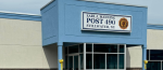 A blue and beige building with a sign reading “Earl J. Manning Post 490, Stillwater, NY” and the American Legion emblem. The entrance features large windows and yellow ribbons tied around the posts.